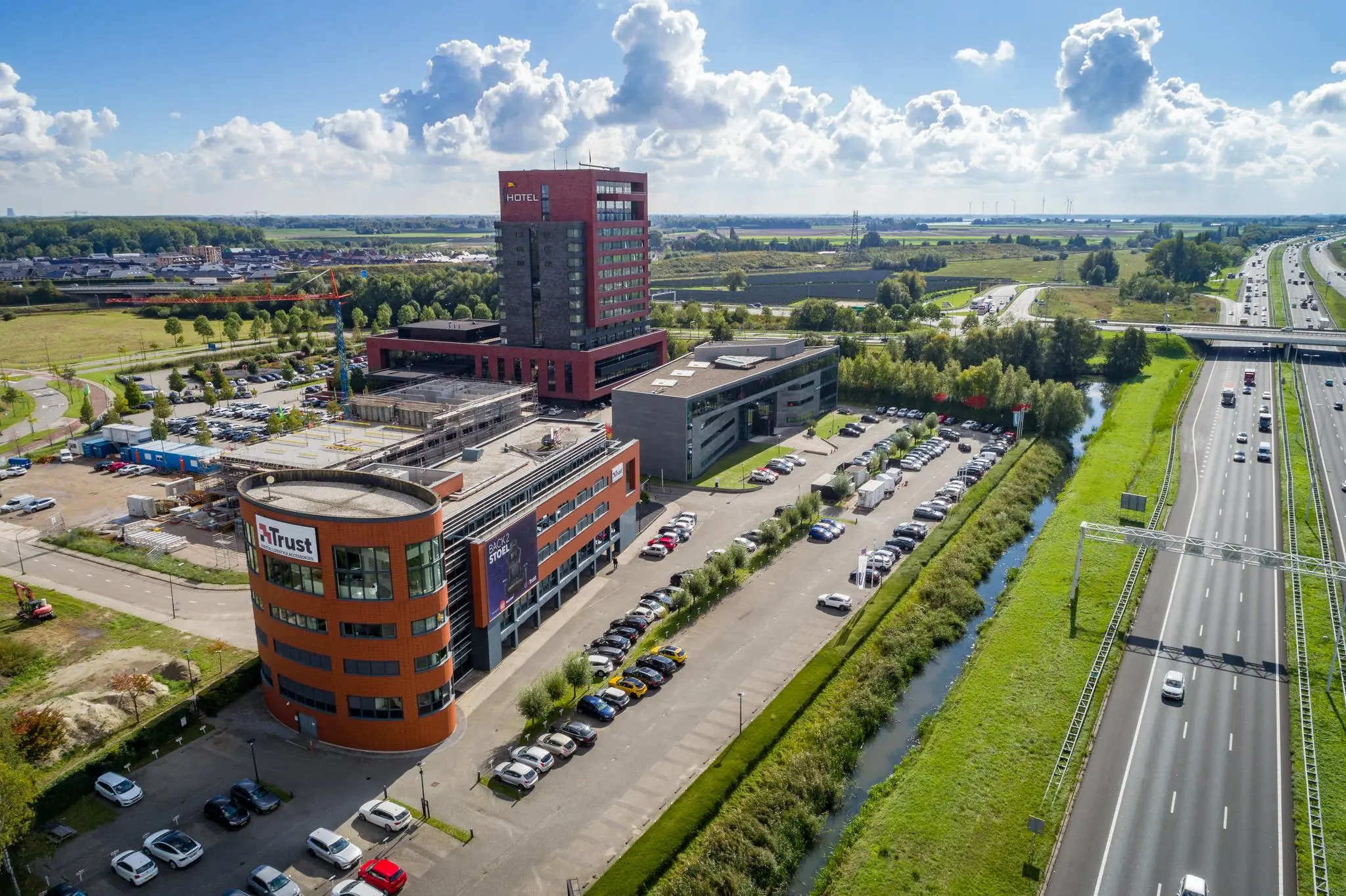 Luchtfoto van de Laan van Barcelona in Almere met kantoorgebouwen, een hotel, parkeerplaatsen en de snelweg A6.